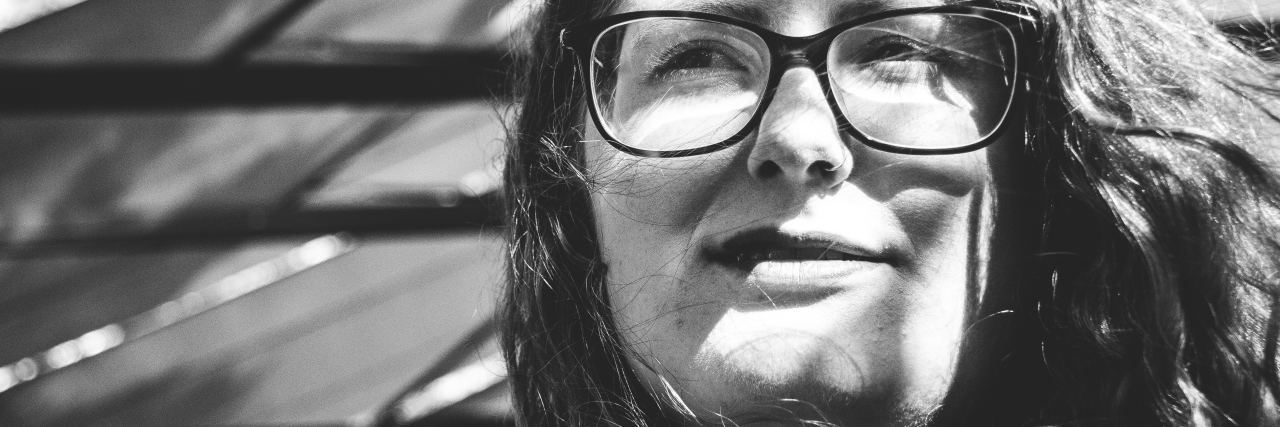 stock black and white photo of woman with glasses squinting in sunlight