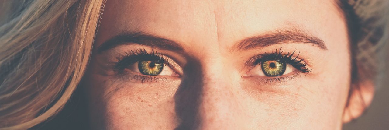 How Bipolar Mania and Hypomania Changes Someone woman looking into camera smiling with close up of eyes