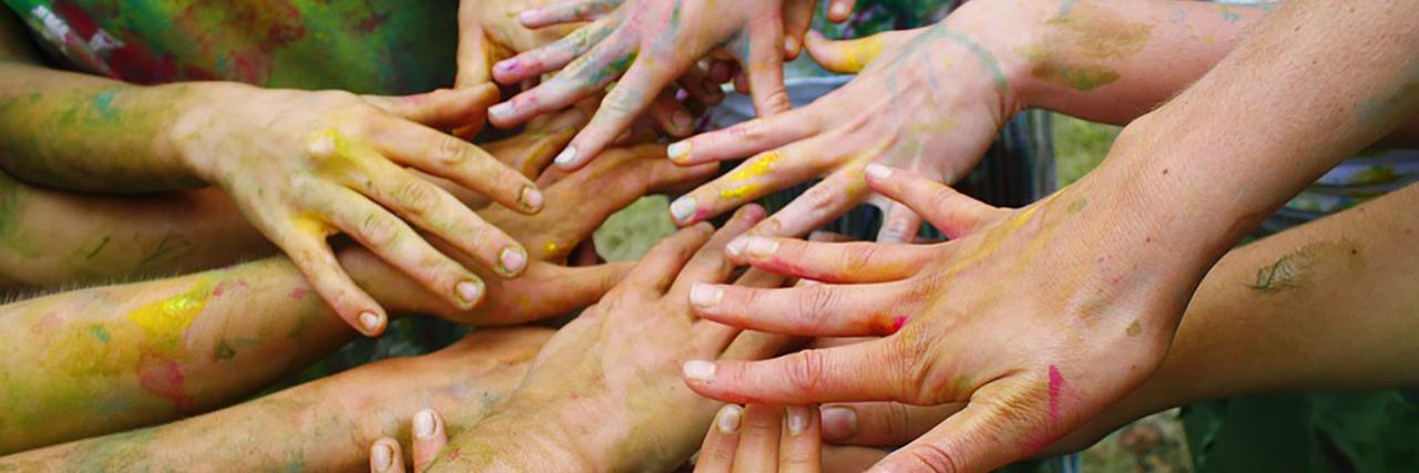 The Challenge of Crafting With Cerebral Palsy Paint-covered hands coming together.