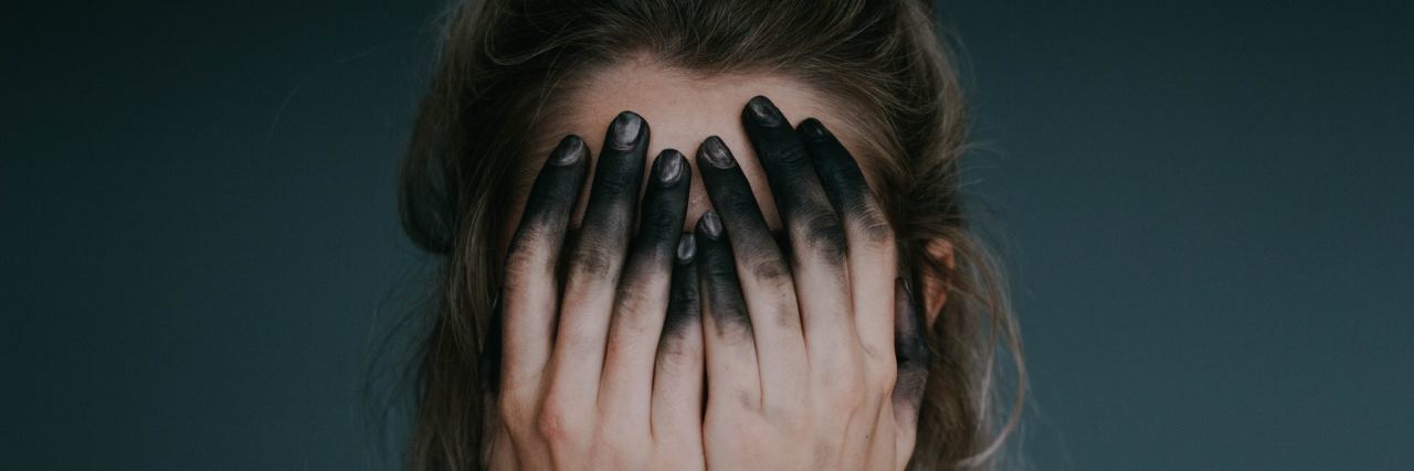 What It Feels Like to Fear Depression Returning woman covering face with hands stained with black ink