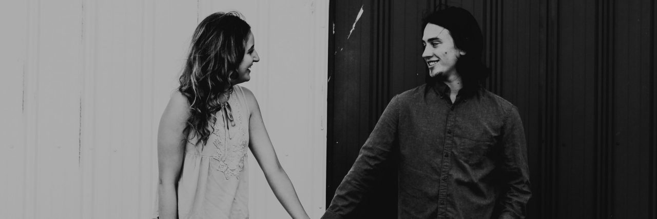 How to Know the Difference Between Love and Bipolar Mania couple holding hands against background of black and white metal