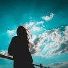 woman silhouetted against vibrant blue sky and white clouds