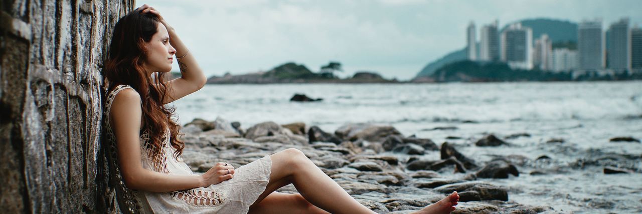 The 9 Symptoms of Bipolar Disorder I Experience woman sitting by sea looking sad