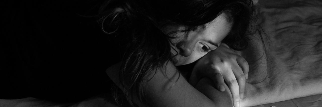 How to Stay Alive When You Want to Die by Suicide black and white photo of young woman lying on bed depressed