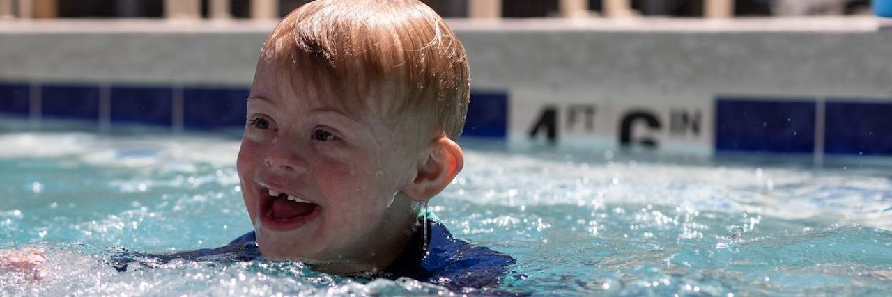 My Son Is Not 'Special' Simply Because He Has Down Syndrome Boy with Down syndrome swimming in pool, smiling