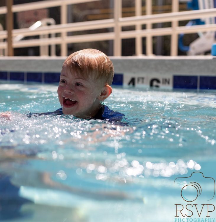 Boy with Down syndrome smiling in pool