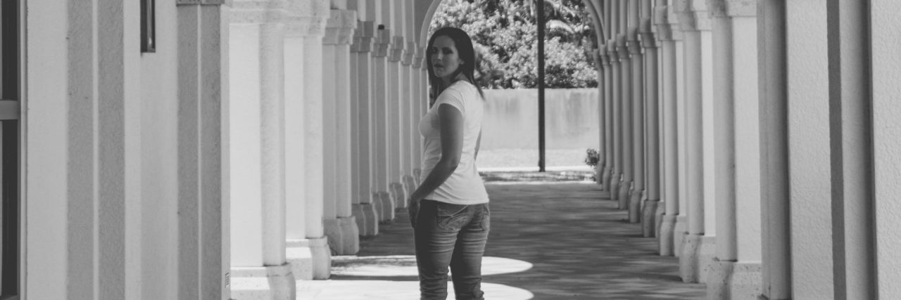 How a Stranger Helped Me Heal From Childhood Abuse black and white photo of woman standing in open arched hallway