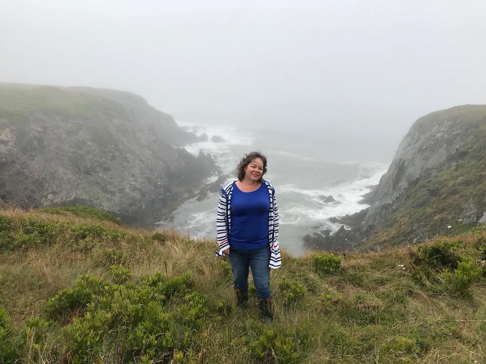 woman standing on a cliff in nova scotia