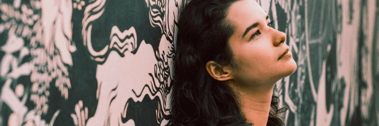 14 Lies People With Bipolar Disorder (Sometimes) Tell A woman leaning against a wall, looking up. text reads: 14 Lies People With Bipolar Disorder (Sometimes) Tell