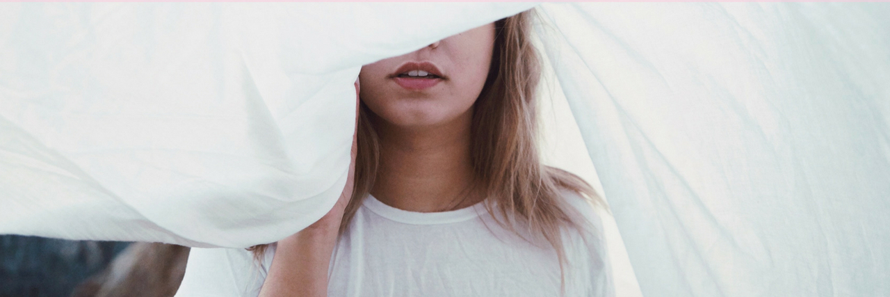 14 Ways People Hide Their Anxiety A woman hiding behind a white curtain. text reads: 14 ways people hide their anxiety