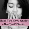 A woman with her hand over her mouth. Text reads: 16 signs you have anxiety - not just stress