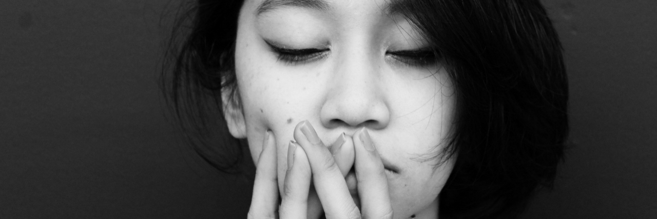 A woman with her hand over her mouth. Text reads: 16 signs you have anxiety - not just stress