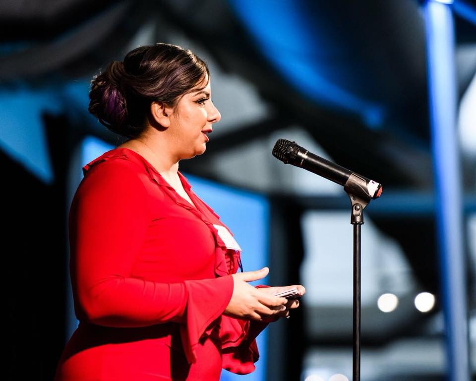 woman speaking into a microphone on stage