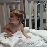Boy in hospital bed sitting up looking to the side
