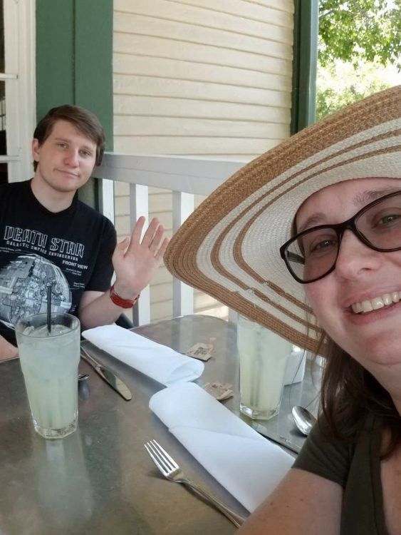 woman and son sitting at a table outside with glasses of lemonade