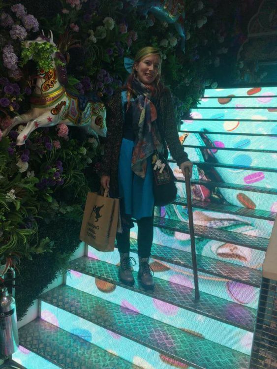 woman standing on colorful staircase with cane