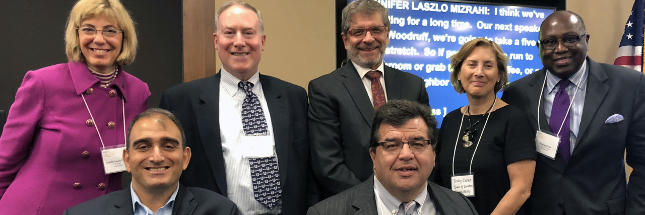 The Employment Rate for People With Disabilities Is Increasing five adults standing, two seated in wheelchairs smiling and posing for a photo