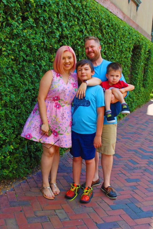 woman, man, toddler boy and older boy standing for family photo