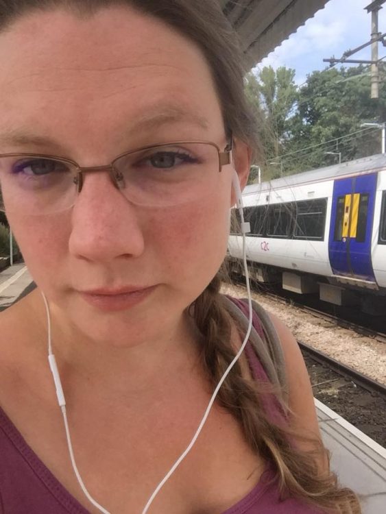 woman wearing headphones outside on train platform
