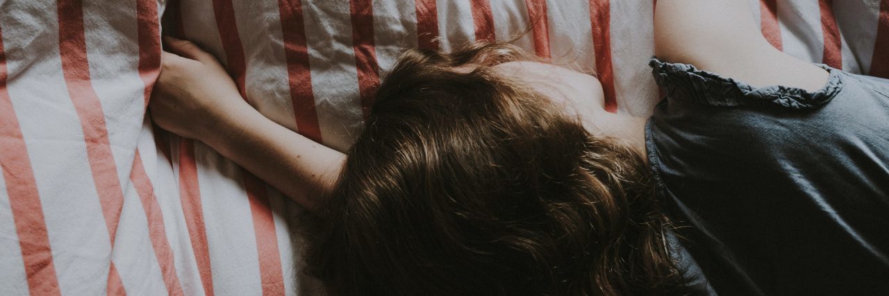 Habits of People With Depression Fatigue young woman lying in bed asleep muted colors