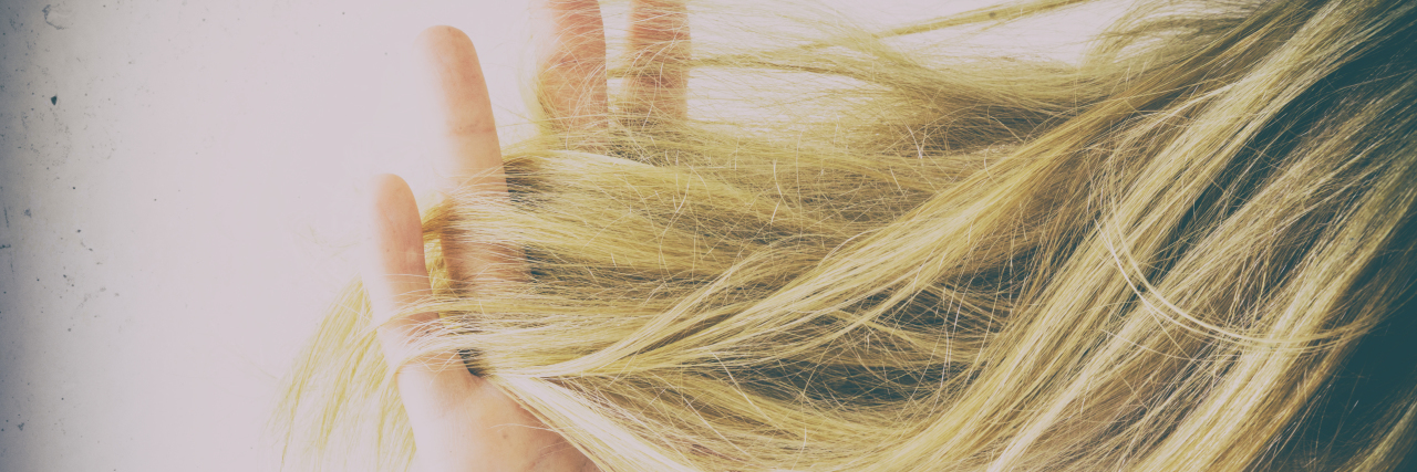 Woman's hand running her fingers through tangled hair.