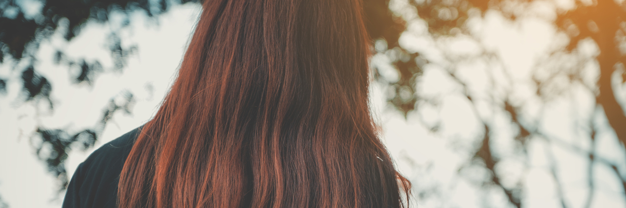 When I Thought My Illness Was Making Me Fall Behind A picture of the back of a woman's head, as she faces a body of water.