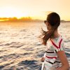woman standing on a boat looking at sunset