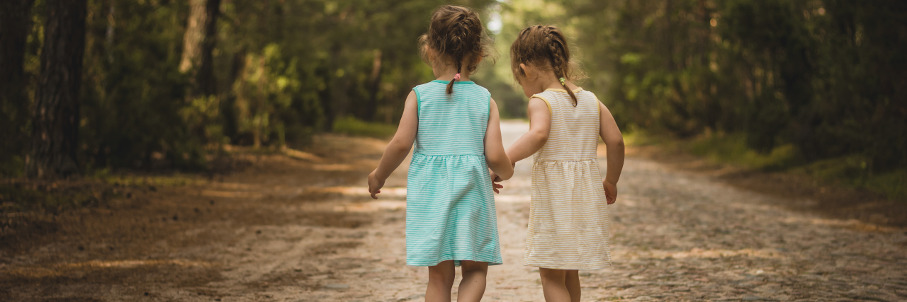 Letter to My Sister With Autism, as I Leave for College Two little girls on a forest road.