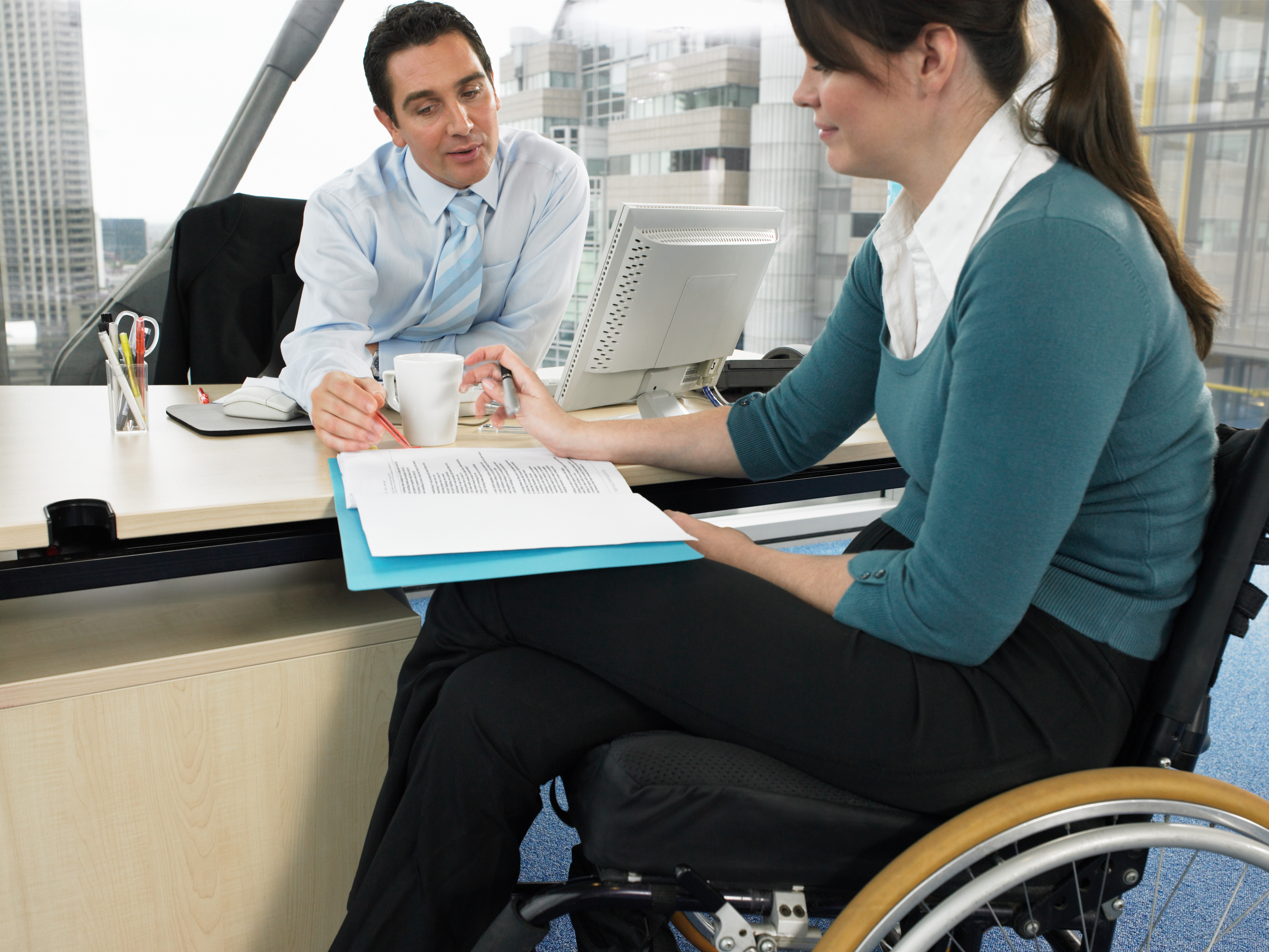 Office workers in meeting. One is a wheelchair user.