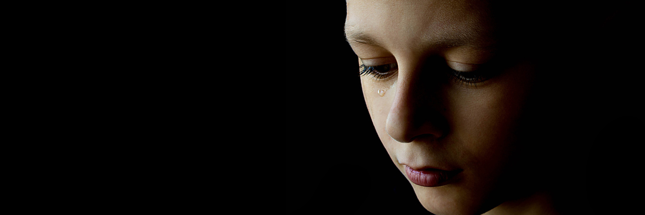 Signs You Grew Up With Bipolar Disorder in Childhood and Adolescence The sad boy with tear in his eye on a black background