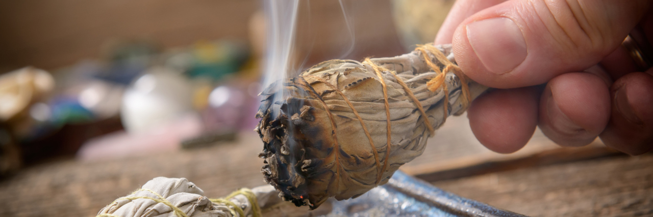 A picture of a man holding and burning incense.