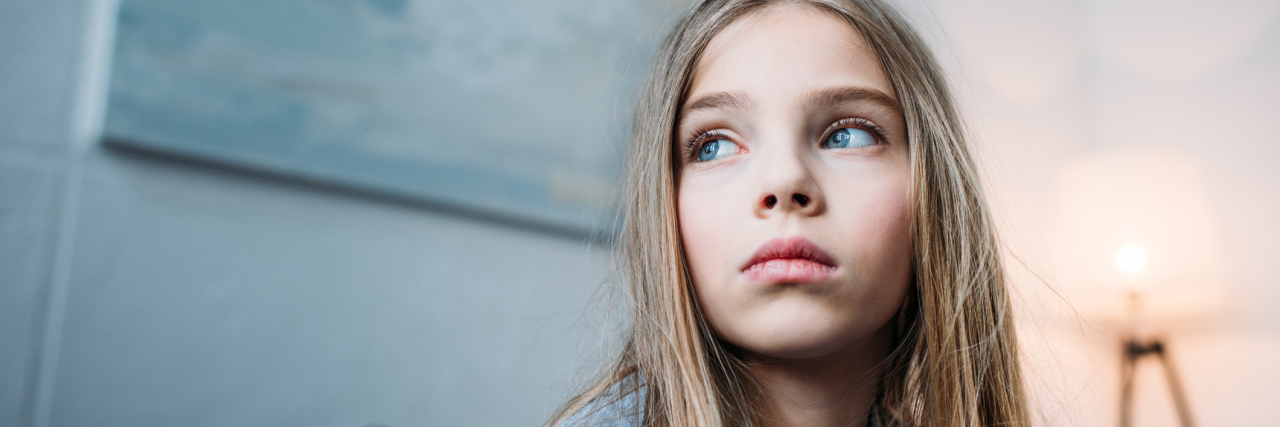 When I Feel I've Given My Child the 'Raw Deal' of Having a Sick Mom A picture of a young girl wearing a serious facial expression, looking away from the camera.