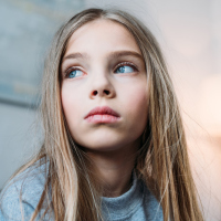A picture of a young girl wearing a serious facial expression, looking away from the camera.