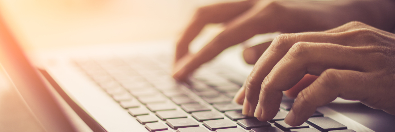 Finding Employment With Autism Person typing on laptop.