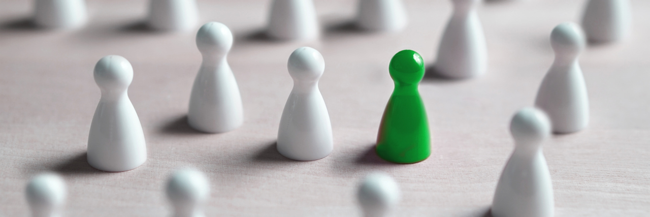 Being Singled Out in School Because of My Disability One green board game piece with many white ones.