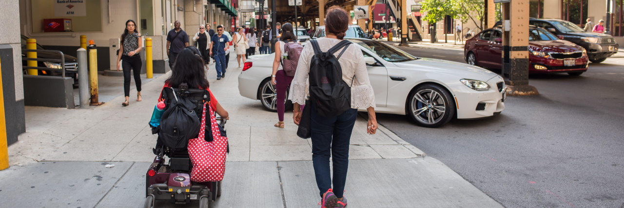 Let's Embrace Our Opportunity to Teach People About Disabilities Woman in a wheelchair rolling down a street in Chicago.