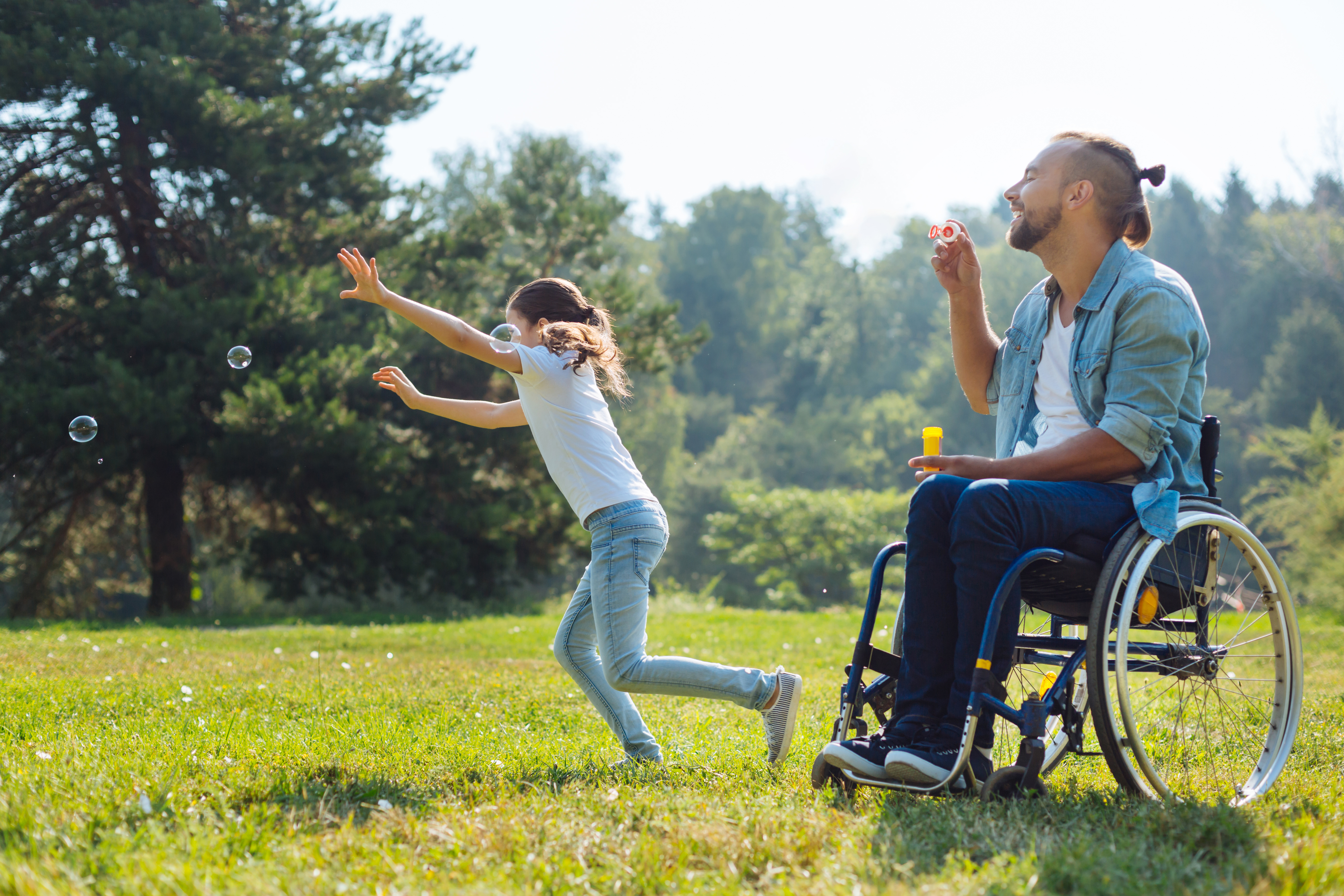 Father in wheelchair playing outside with his daughter.