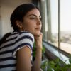 Thoughtful young beautiful woman looking through window at office