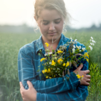 Girl in a field holding flowers.