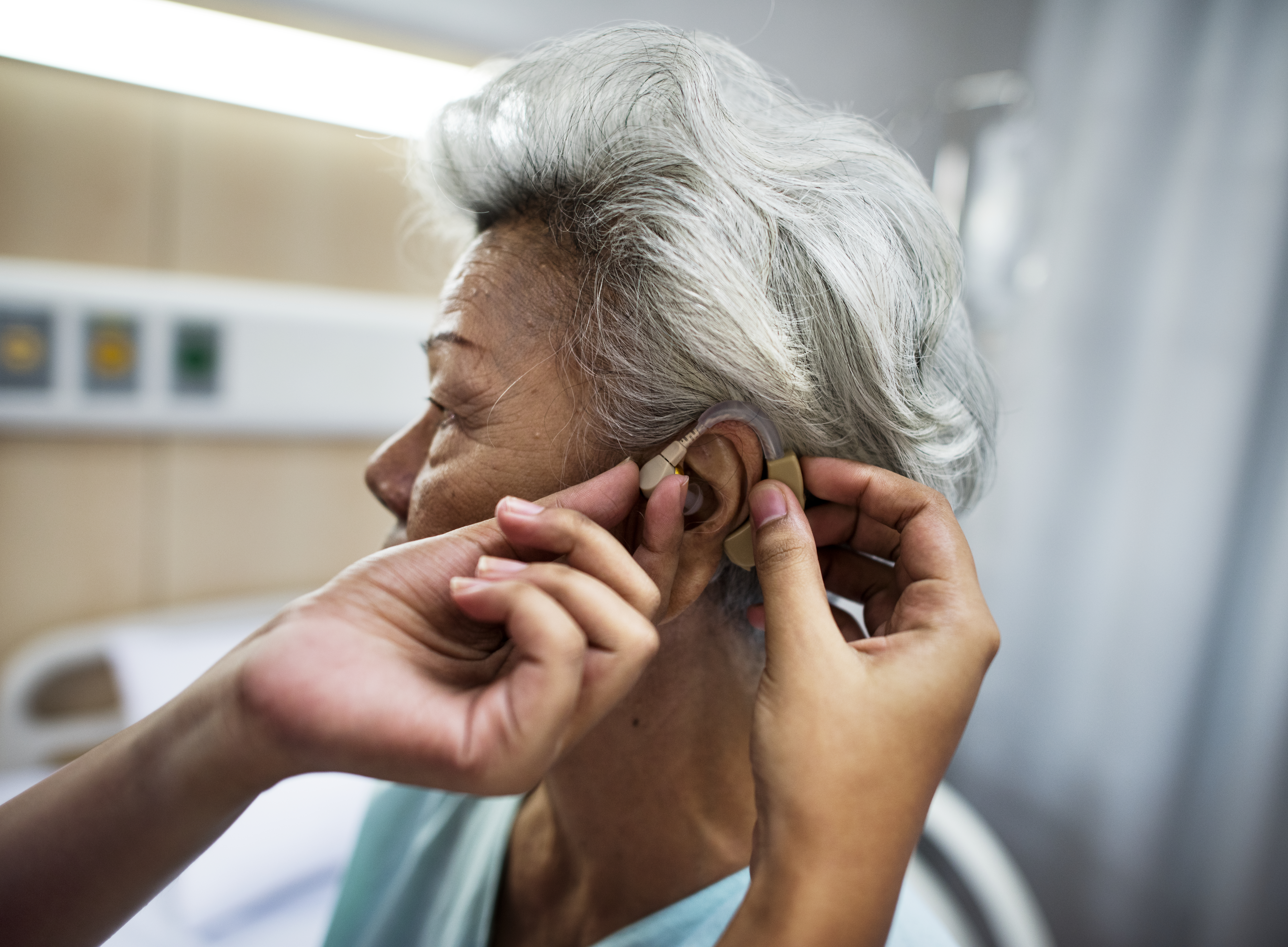 Elderly woman being fitted for a hearing aid.