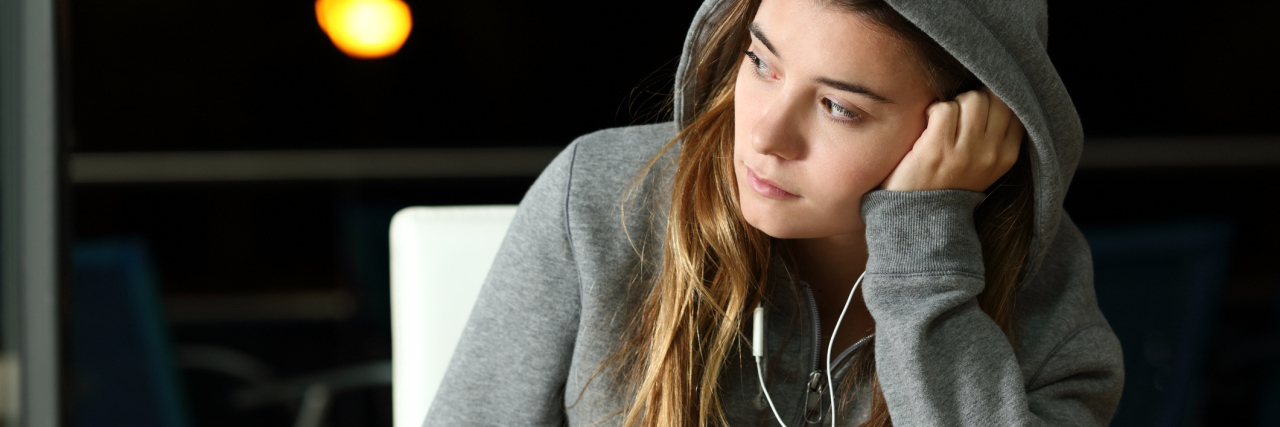 woman wearing a gray hoodie and listening to music while looking away
