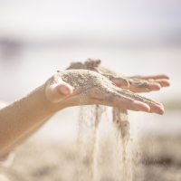 A picture of a woman with sand falling between her fingers.