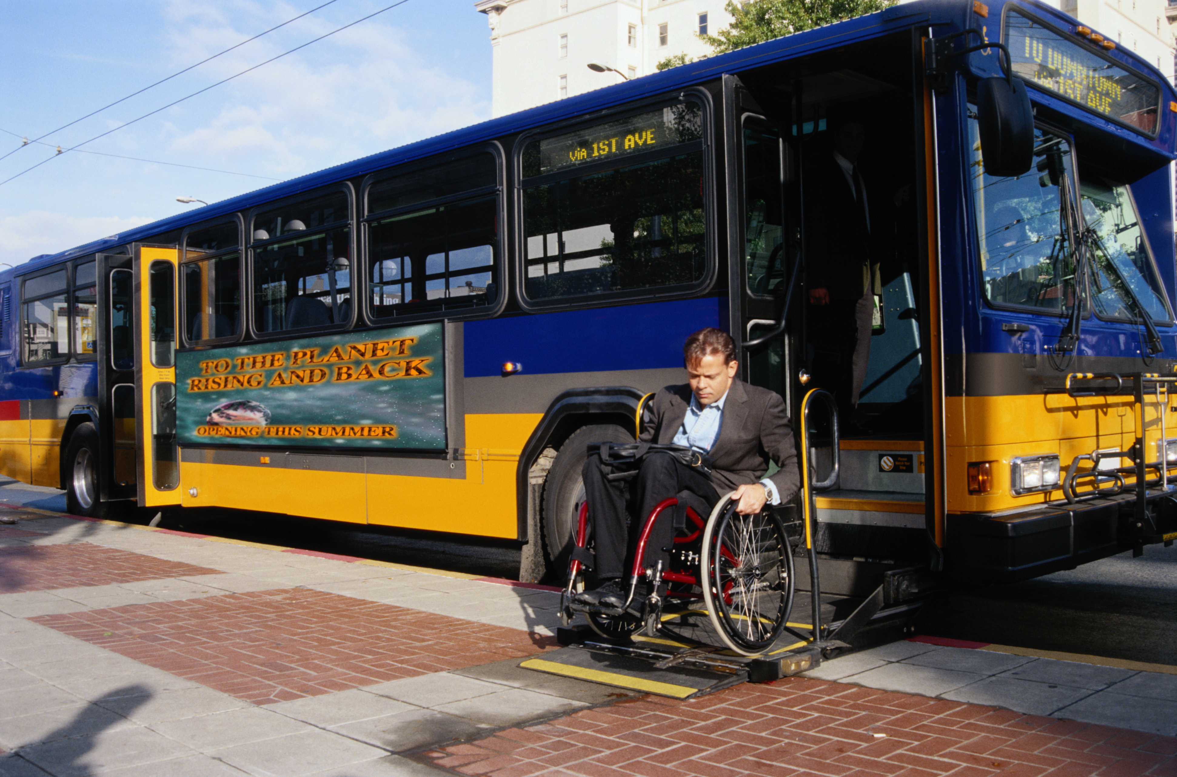 Man in wheelchair getting off a bus.