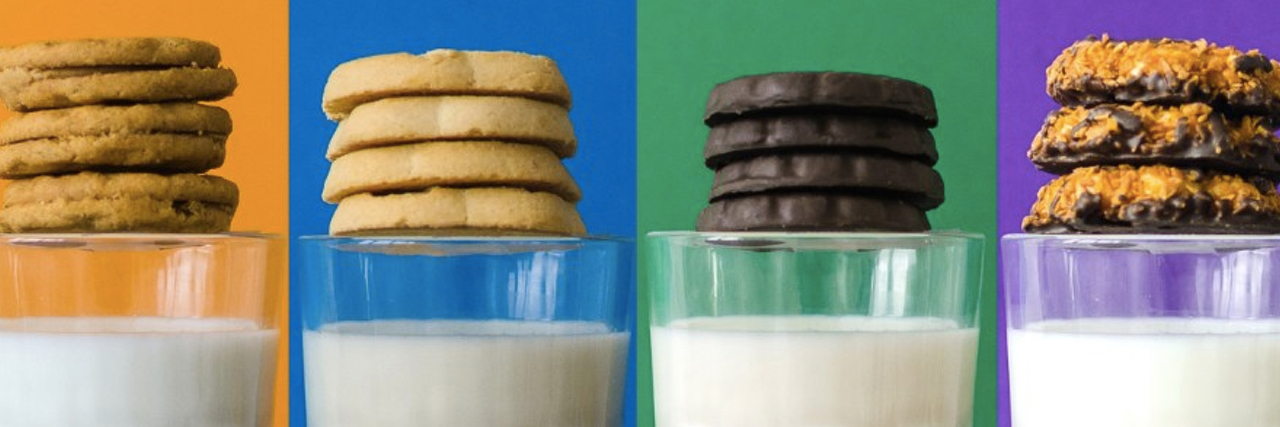Four rows of Girl Scout cookies sitting over glasses of milk.