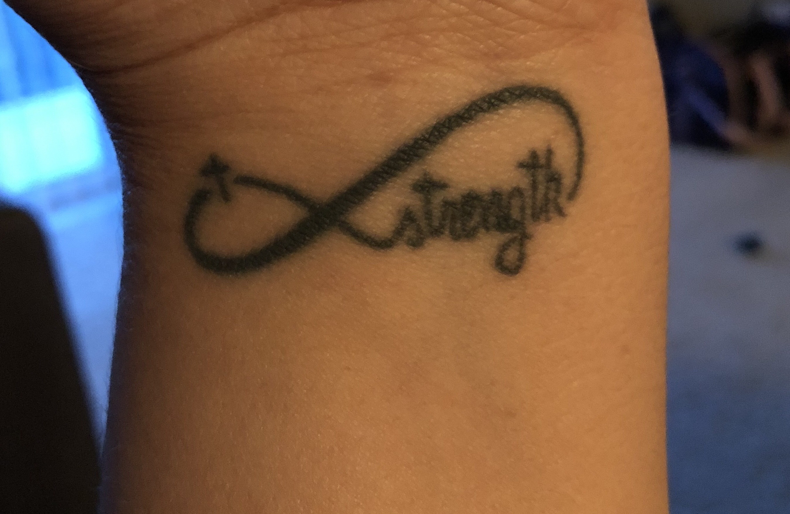 tattoo of an infinity sign with a cross and the word 'strength' in it