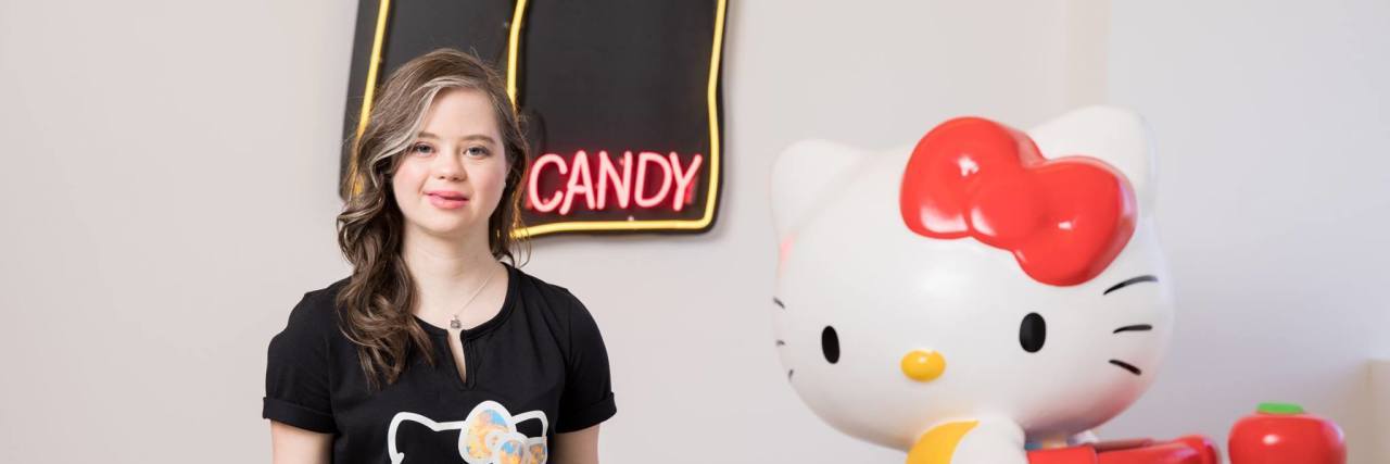 Megan Bomgaars Teams Up With Sanrio's Hello Kitty Megan Bomgaars wearing shirt that reads "I can and I will" and a figuring of Hello Kitty next to her