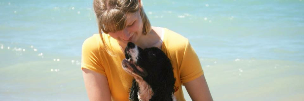 Mighty Pets Support Their Humans Through Health Challenges Woman on the beach with her Springer spaniel.