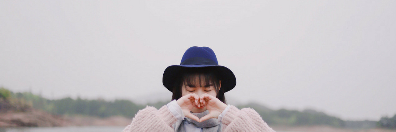 To the Person Who Hates Themselves Today A woman making a heart with her hands. To the person who hates themselves today