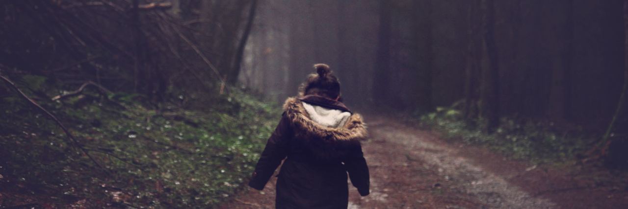 little girl walking alone through forest