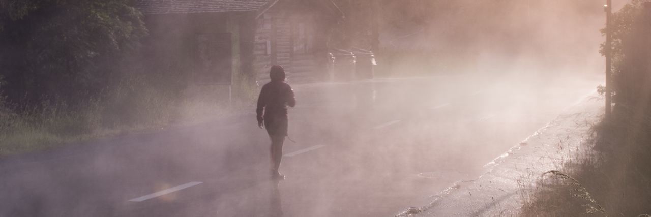 Finding Peace With My New Bipolar Disorder and Psychosis Diagnosis woman walking along foggy road with trees and sunlight